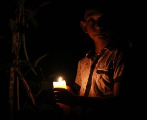 young boy holding a candle in the dark