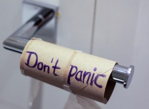 empty toilet paper roll on holder with "Don't Panic" written on it