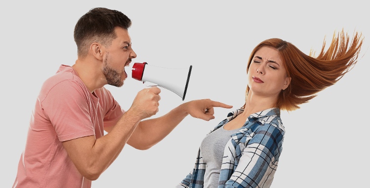 man with bull horn hollering at a women who is being blown backward by the tirade